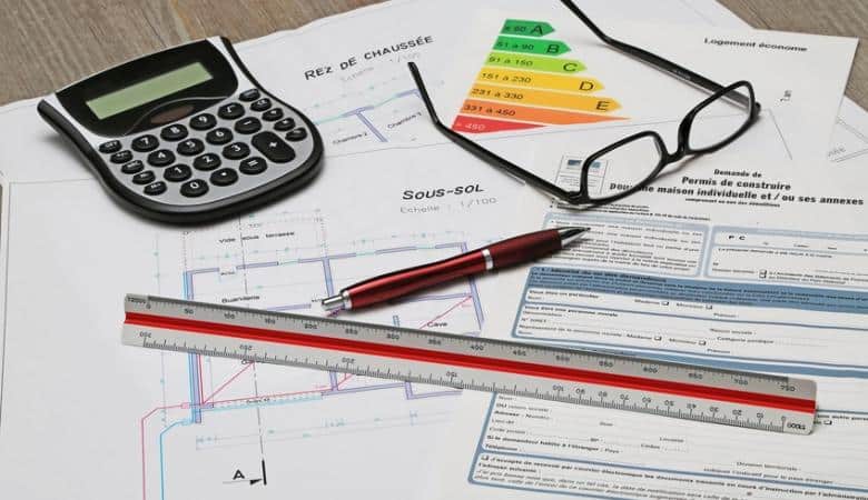 calculatrice, stylo et papiers d'estimation avec la performance énergétique et les caractéristiques du bien immobilier