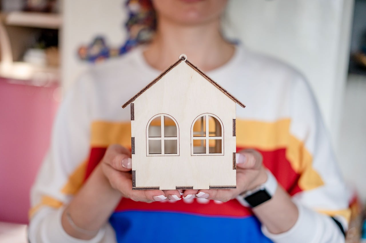 Une femme qui tient une maison miniature dans ses mains