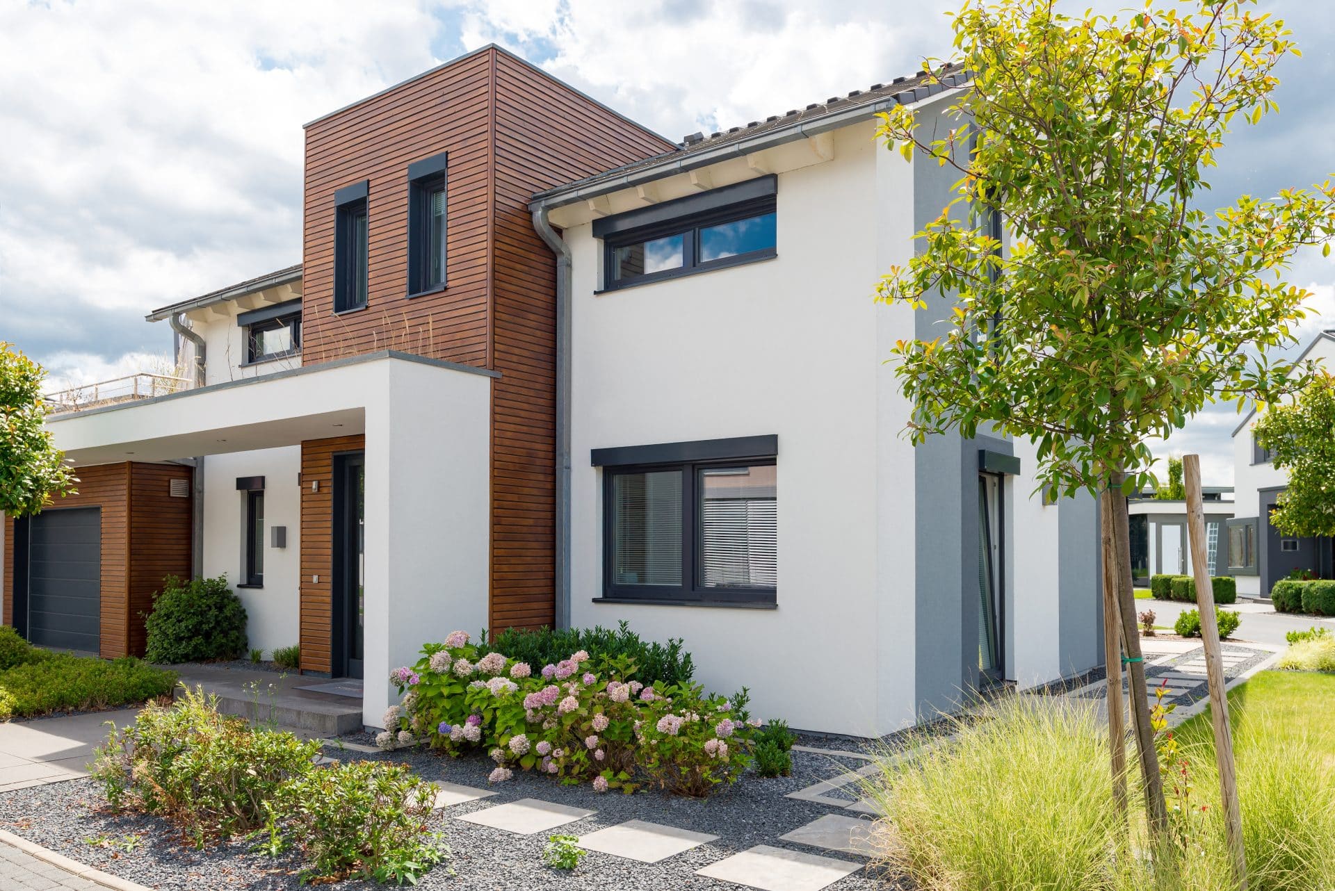 maison vue d'extérieur avec façade aux murs blancs et en brique et petit jardin